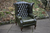 A LEATHER CHESTERFIELD ANTIQUE GREEN WING-BACK ARMCHAIR.